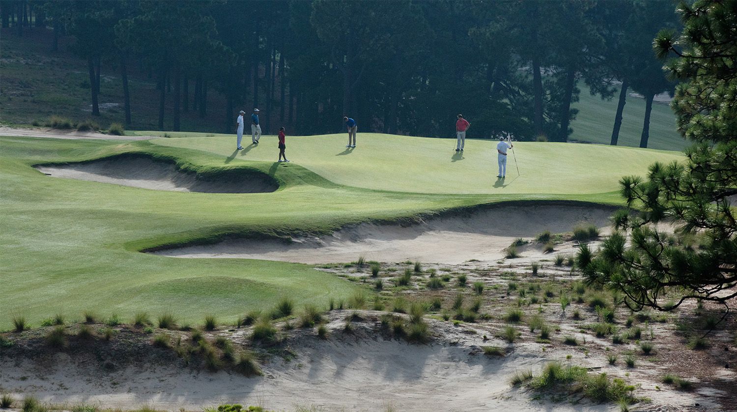 A group of golfers putt on Pinehurst Number 2's green