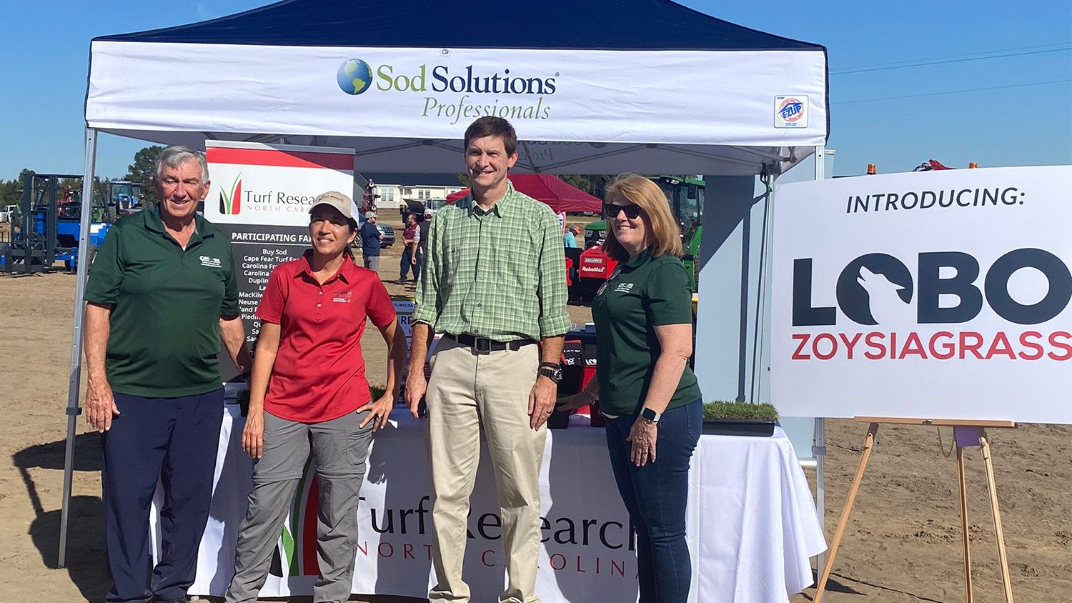 A group stands in front of a Sod Solutions turfgrass display