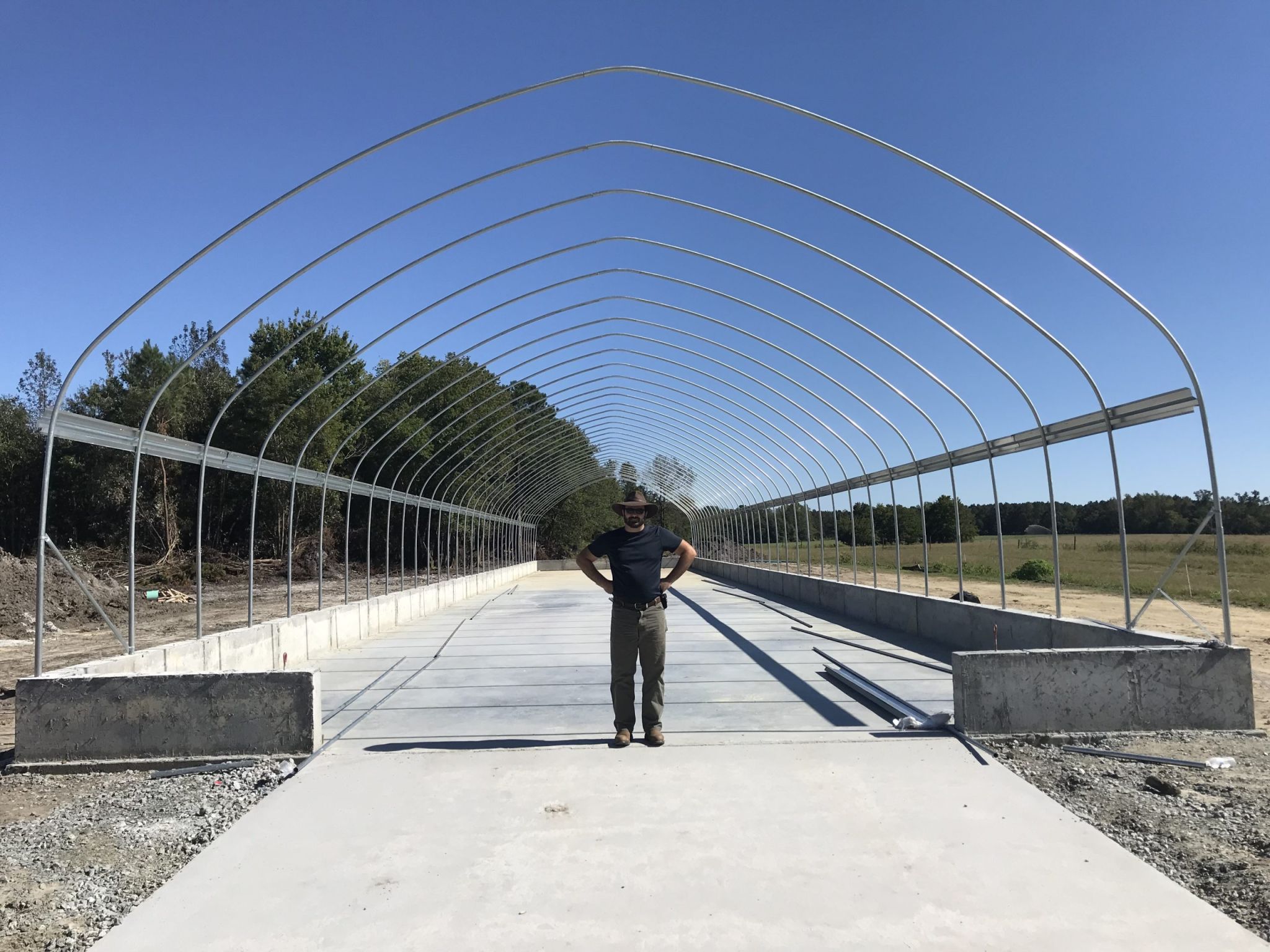 A man standing in a greenhouse dryer under construction