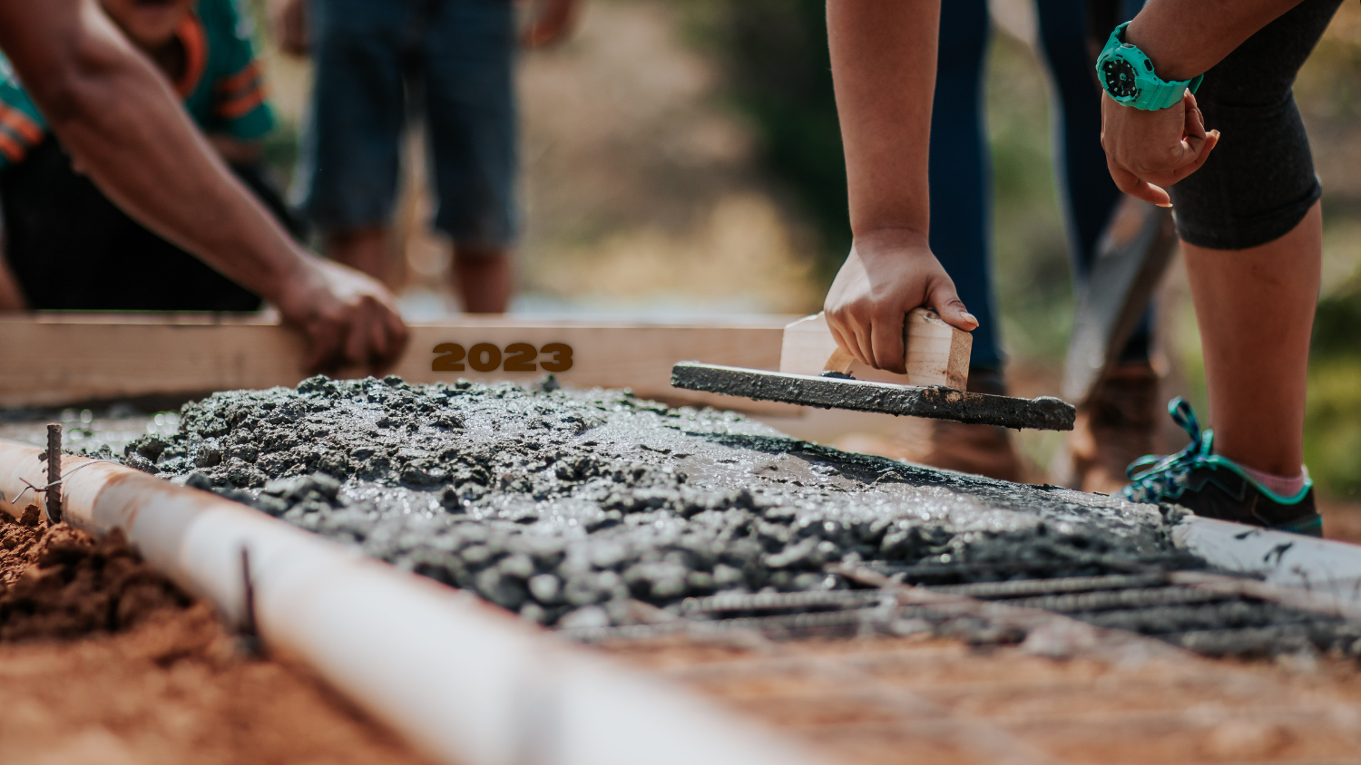 Hands working with cement in the dirt.