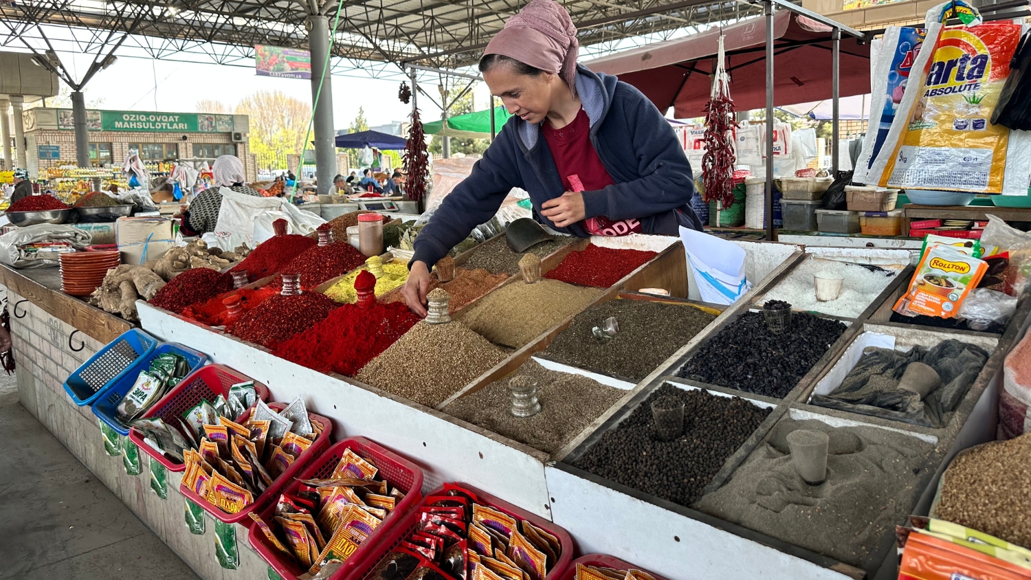 An Uzbek woman tends a market stand of spices