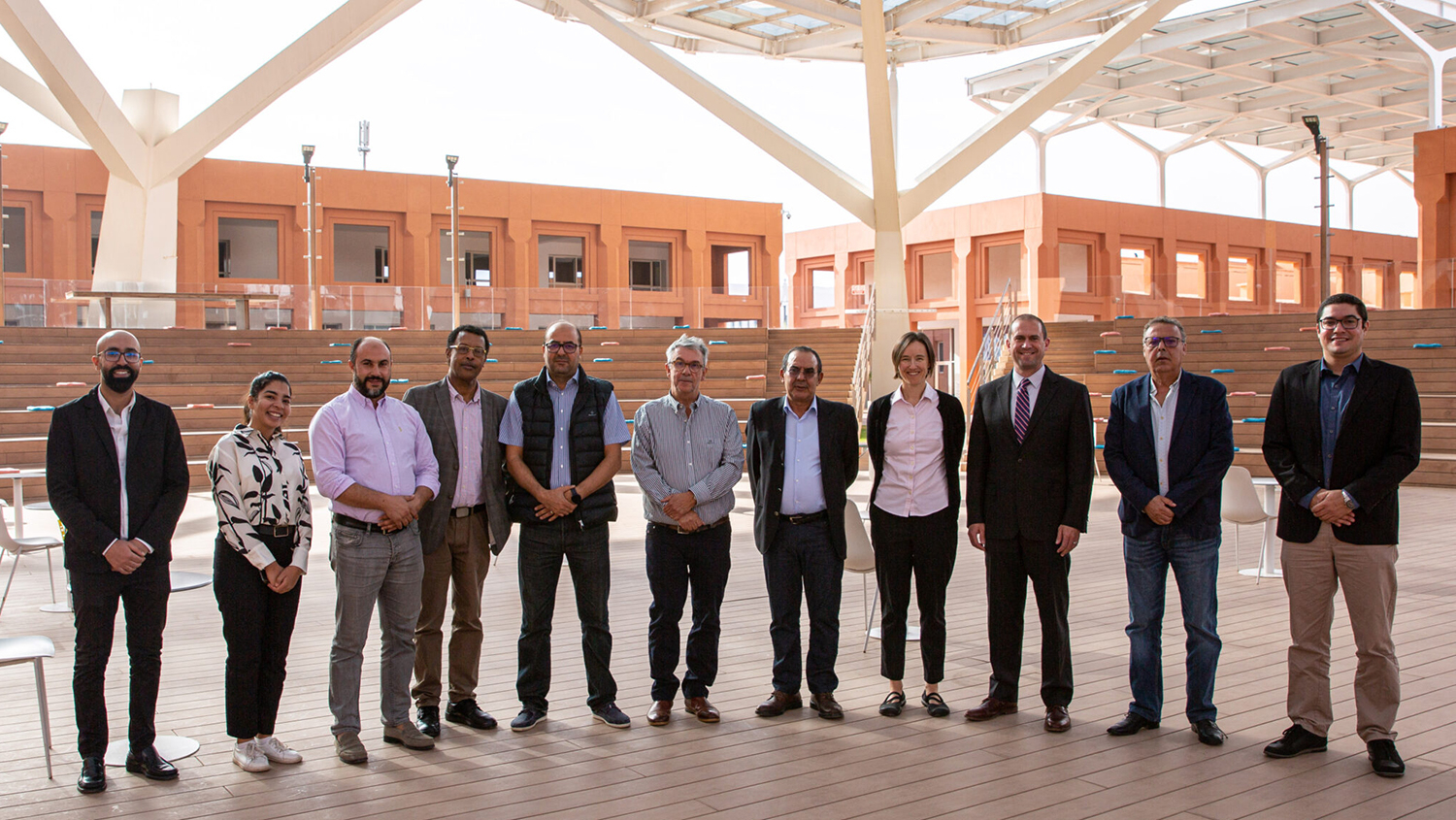 NC State faculty visiting UM6P in 2022. Group pose in a long line facing the camera while standing in a brick courtyard with brick buildings in the background.