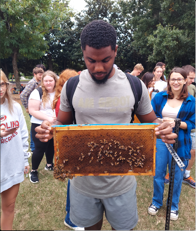 Jaleel Hewitt holds a honeybee frame at an NC State campus event