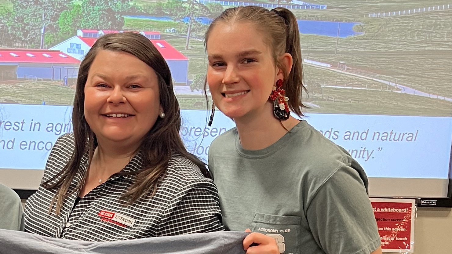 Woman and female student holding a gray t-shirt