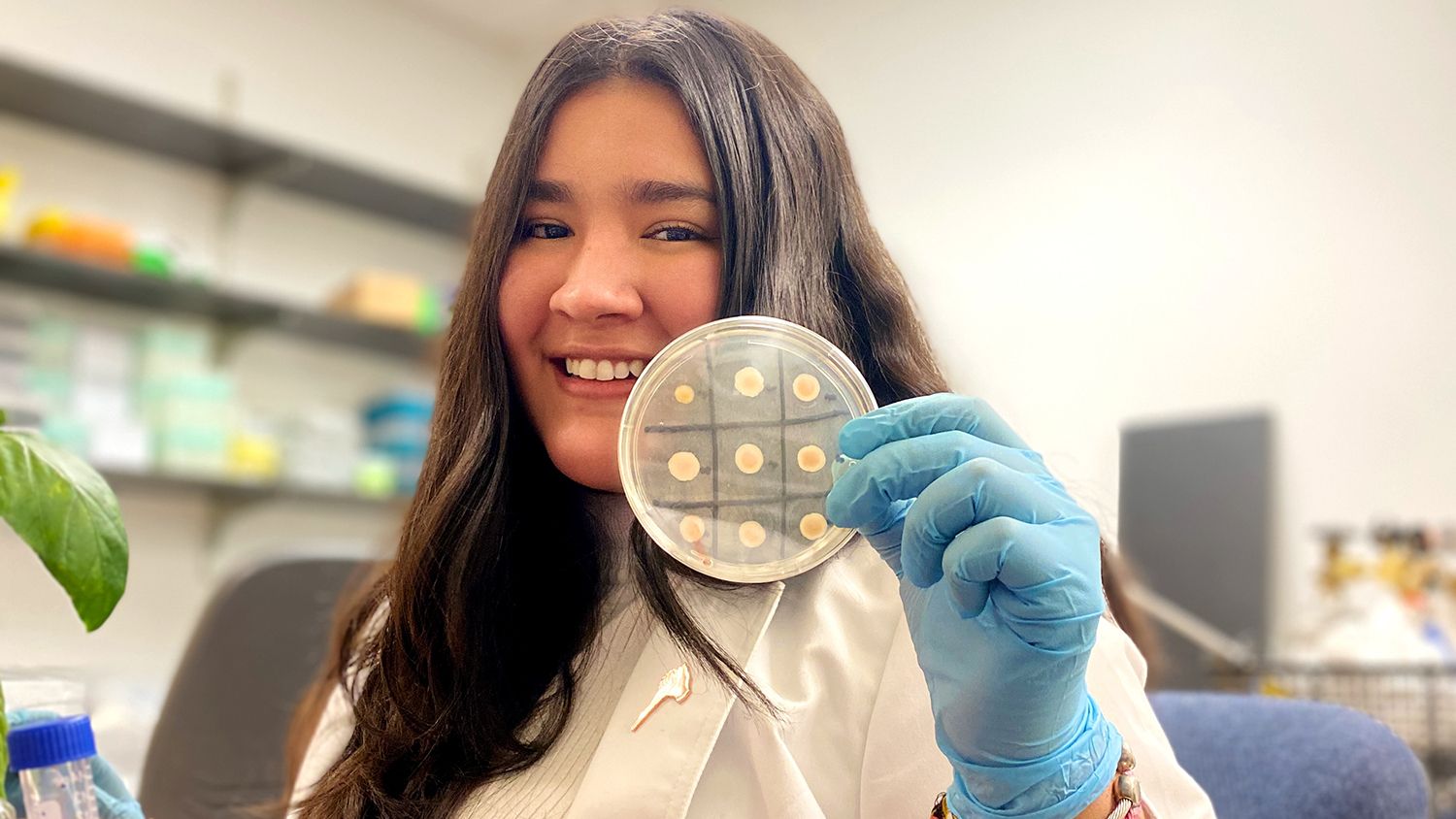 student holding petri dish of cultures