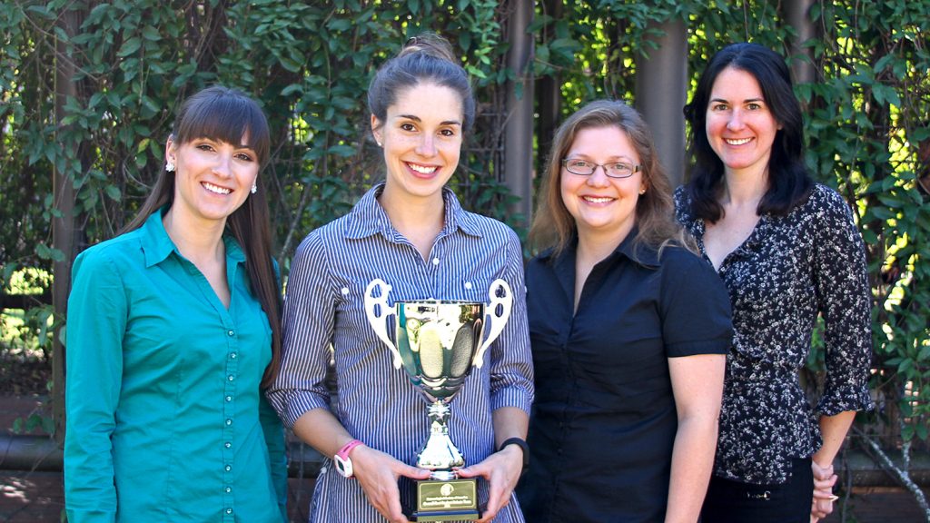 Four debate team members pose with trophy