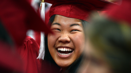 A student beams with happiness as they wear cap and gown regalia