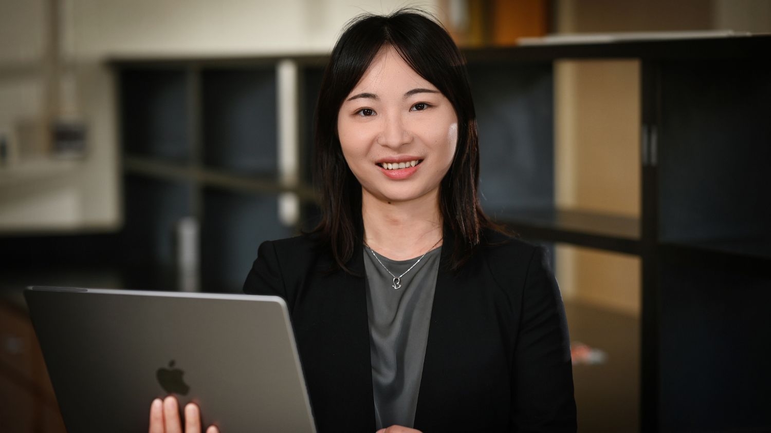 Minliang Yang holding a computer and smiling