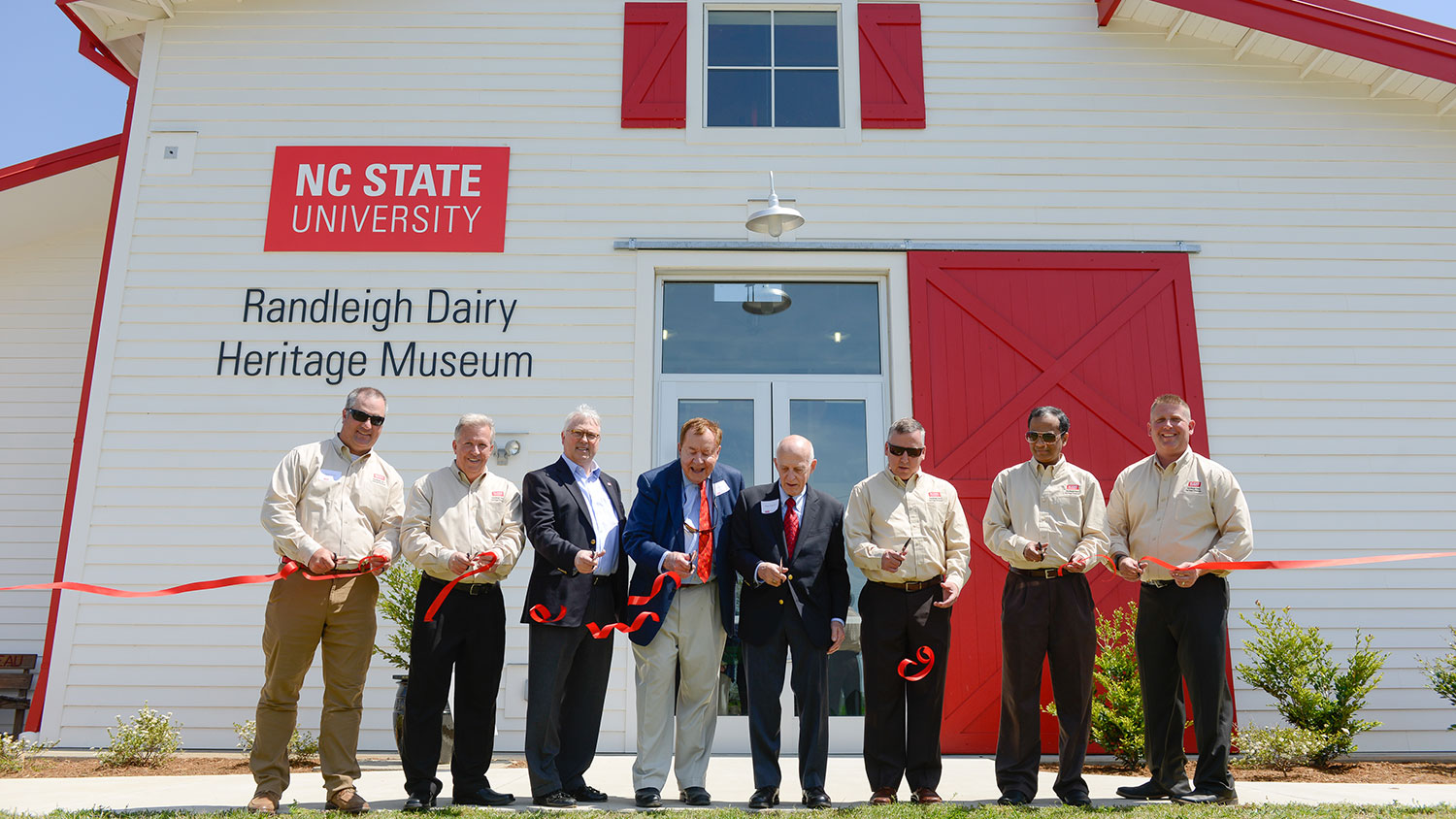 Group cutting ribbon in front of Randleigh Dairy Heritage Museum