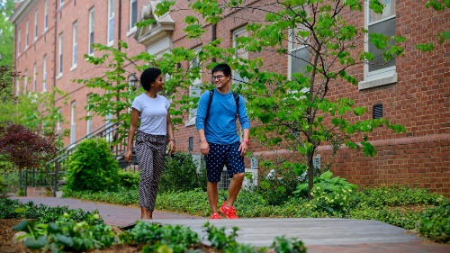 Two students walking by dorms
