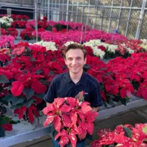 Brandan Shur in greenhouse surrounded by poinsettias