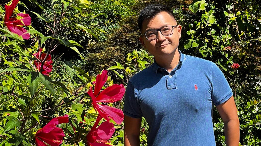 Dr. Hsuan Chen with a blooming hibiscus tree.
