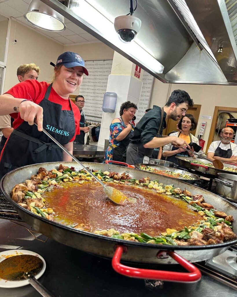 Gente cocinando paella en la cocina.