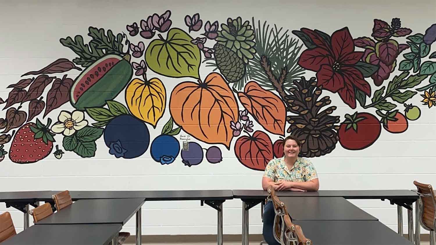 Sarah Remington with her plant mural at HFL classroom