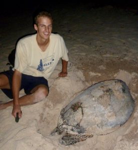 Andrew Maurer posing with a Hawksbill as it just finished laying its eggs and starts to cover the hole with sand.