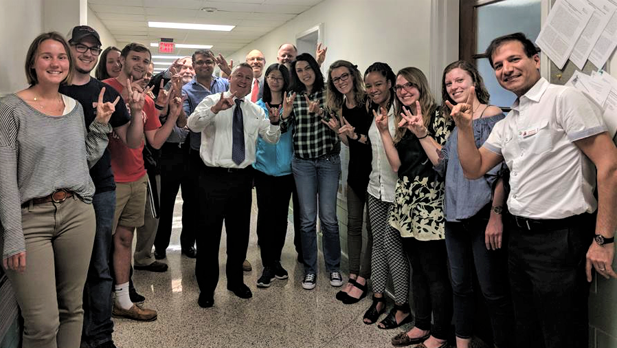 Group of NC State students, faculty, Borlaug Fellow, and Dean Linton smile together in a campus hallway