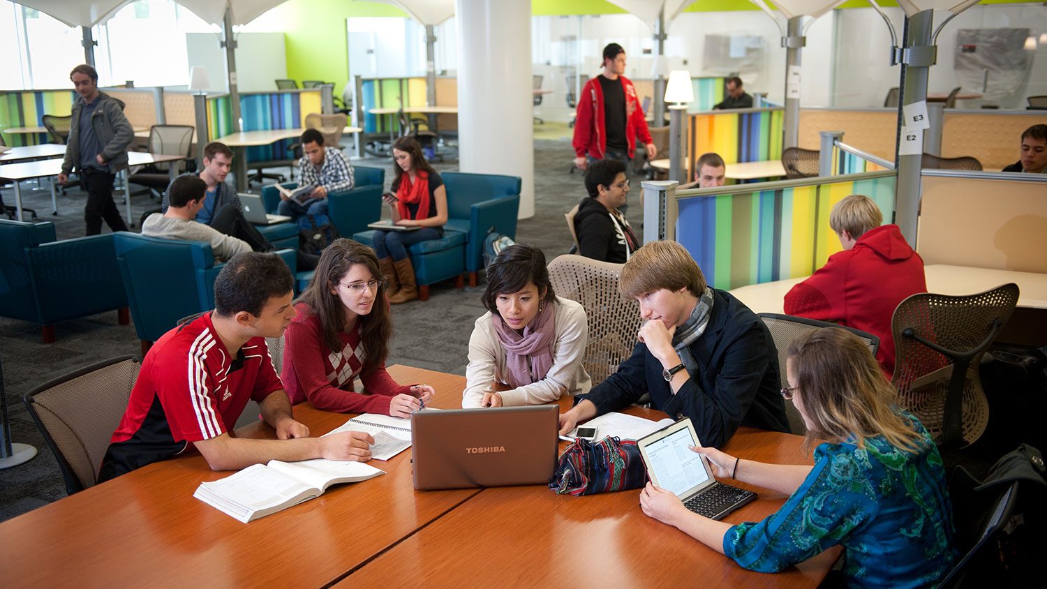 People gathering around a table looking at a computer