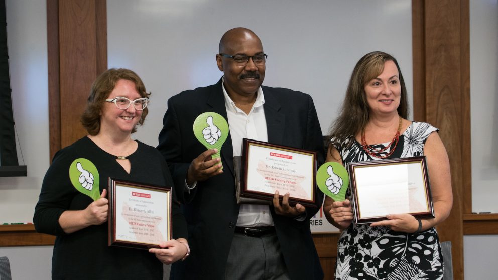 Photo of three faculty members holding framed certificates and thumbs-up signs.