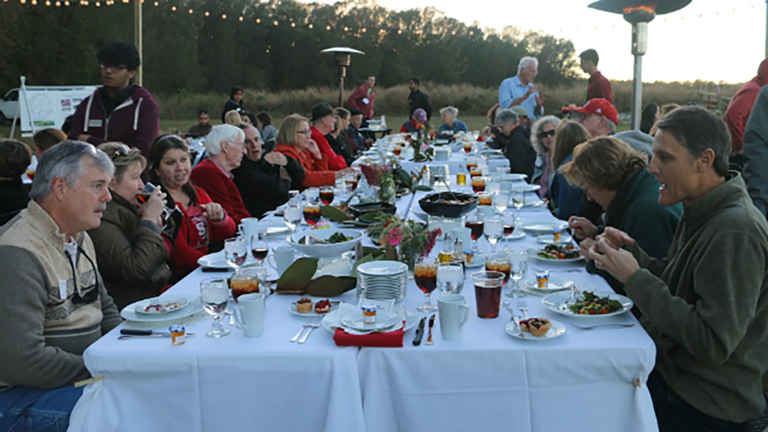People seated at a long table with white tablecloth
