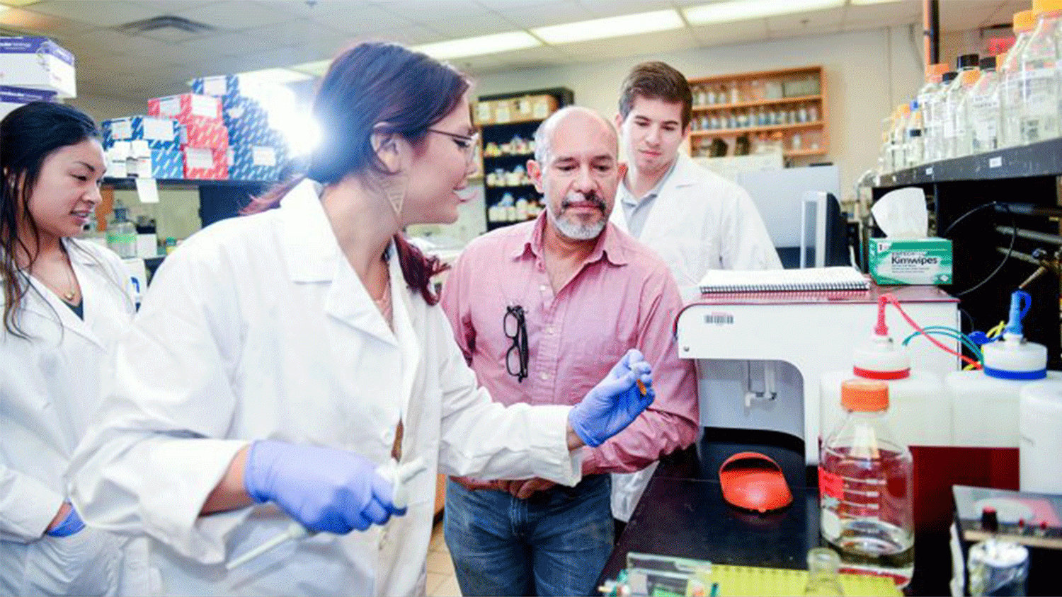 Scientists in a lab working on a piece of lab equipment