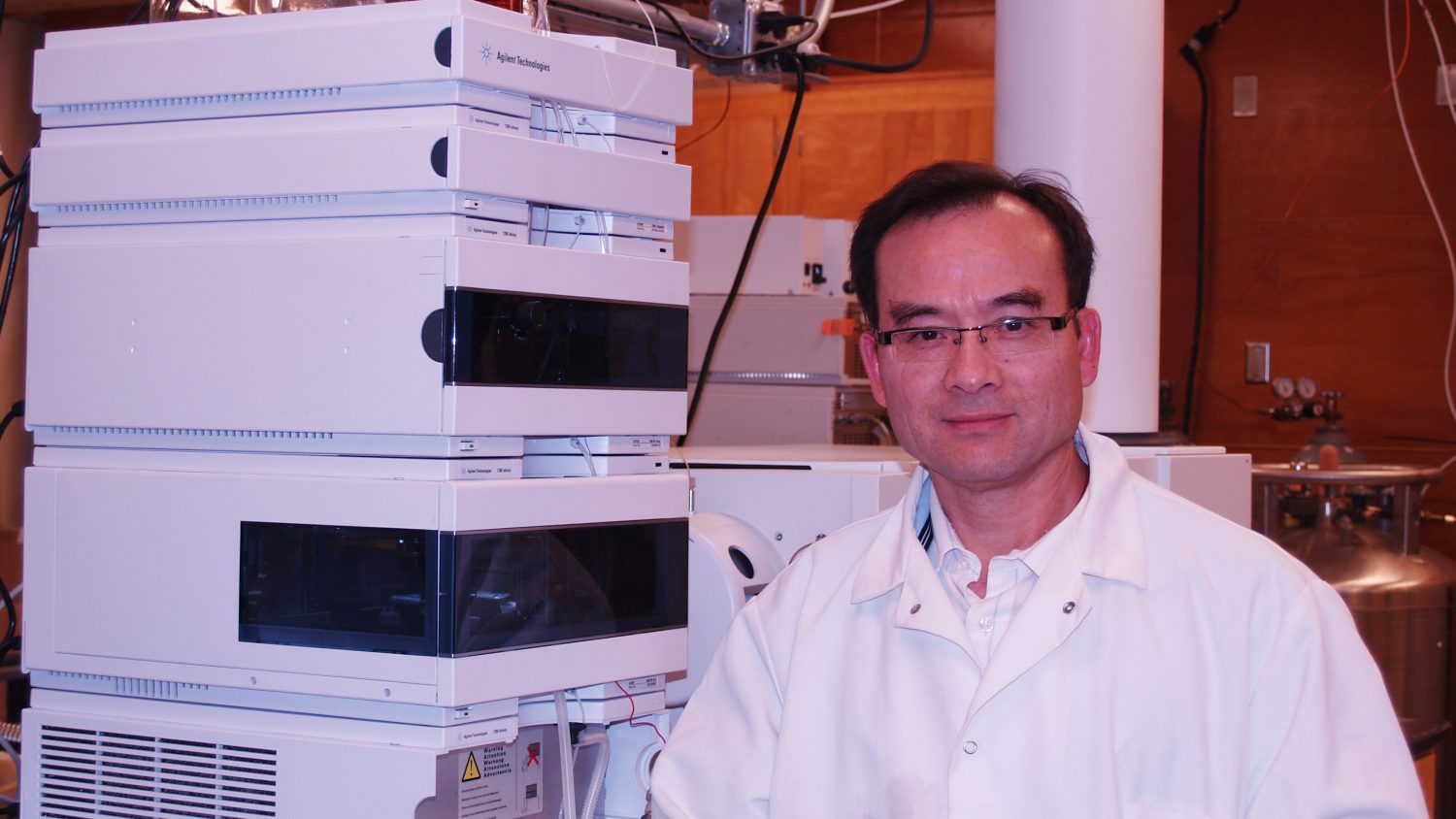 Photo of a scientist in lab coat near equipment