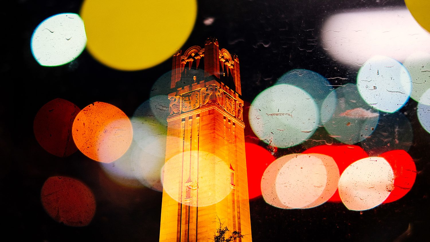 NC State Belltower at night with a glowing spotlight effect