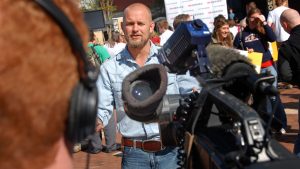 Man standing for an interview infront of a camera.