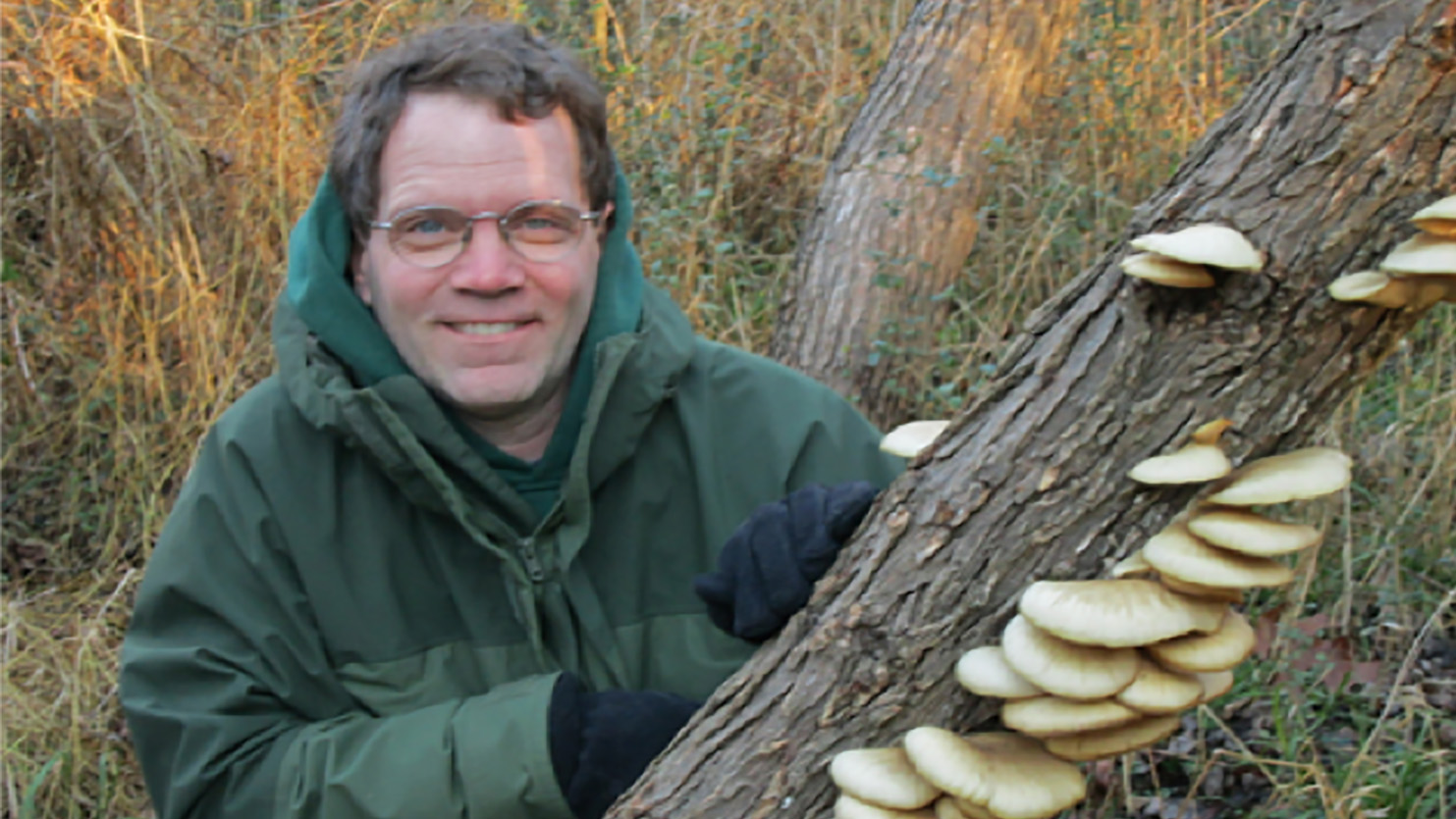 Man holding log with fungi