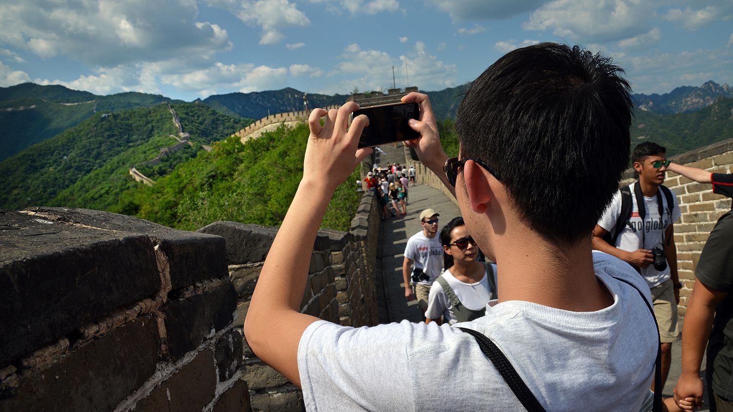 Back of man using his cell phone to take a photo of the Great Wall of China