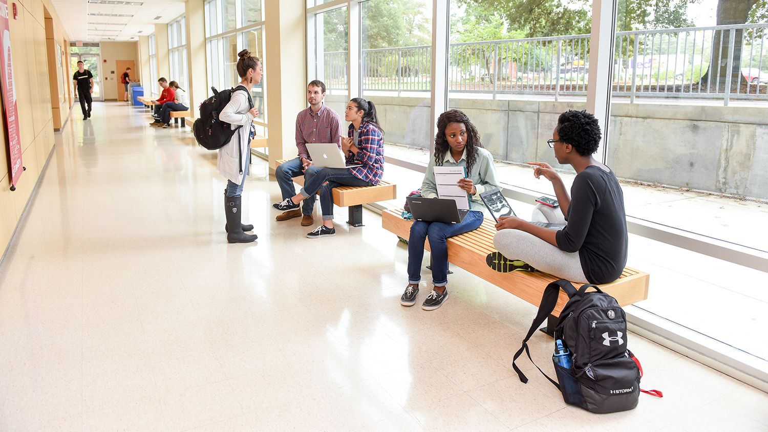 Two groups of people talking in a hall way.