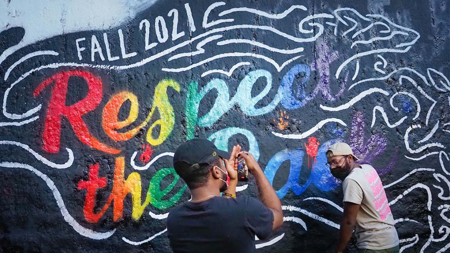 Two Black students painting a beautiful rainbow mural