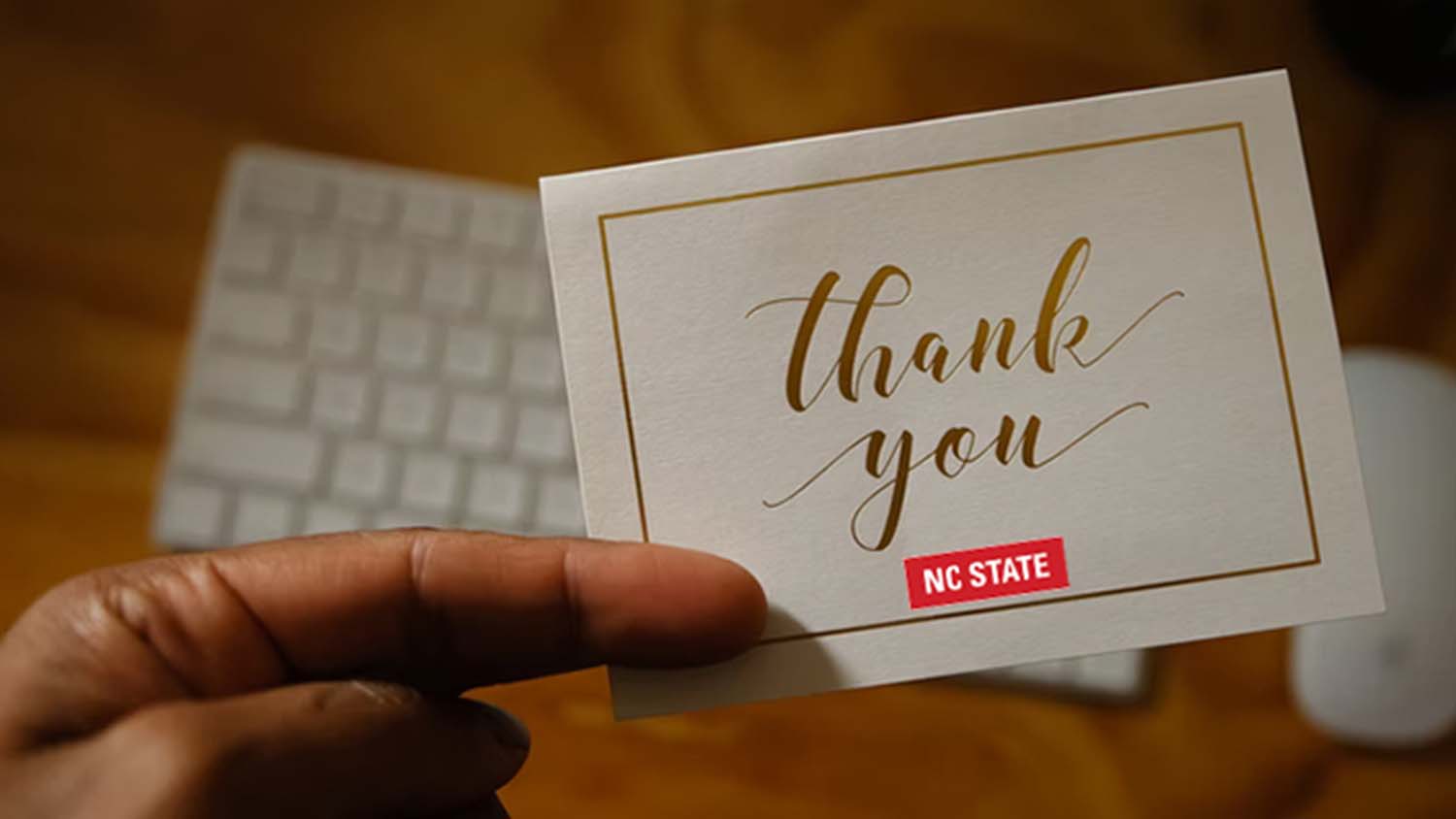 Hand holding university thank you note