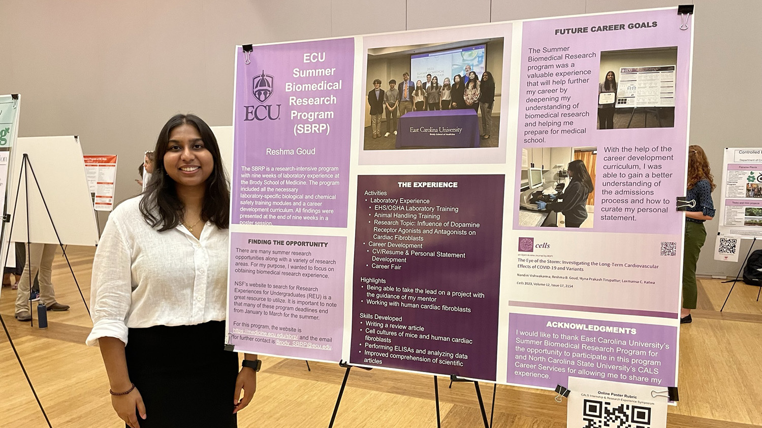 female student standing next to poster