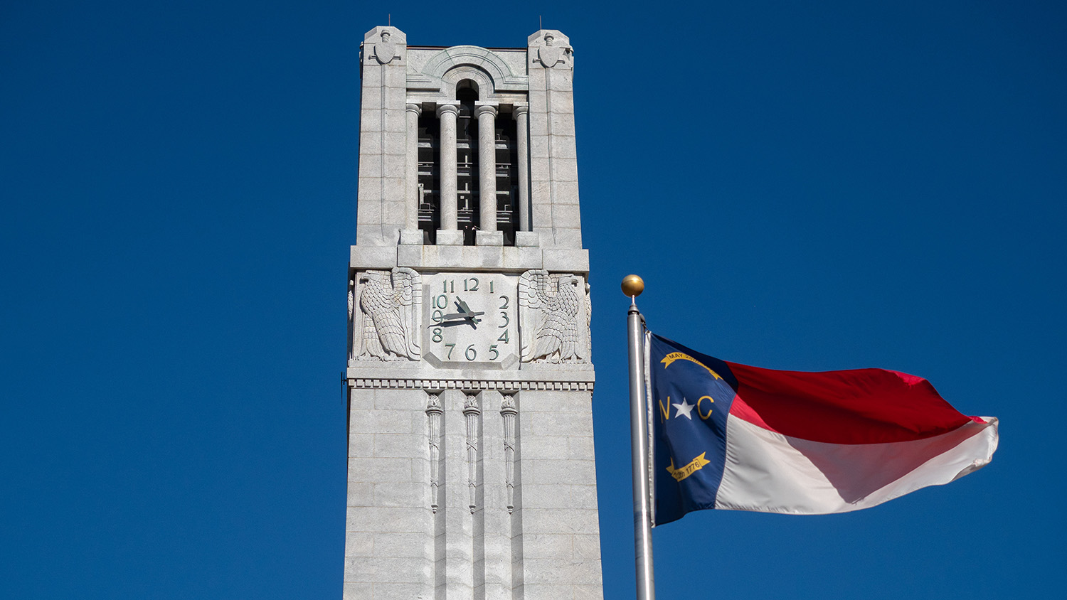 white clock tower with north carolina state flag