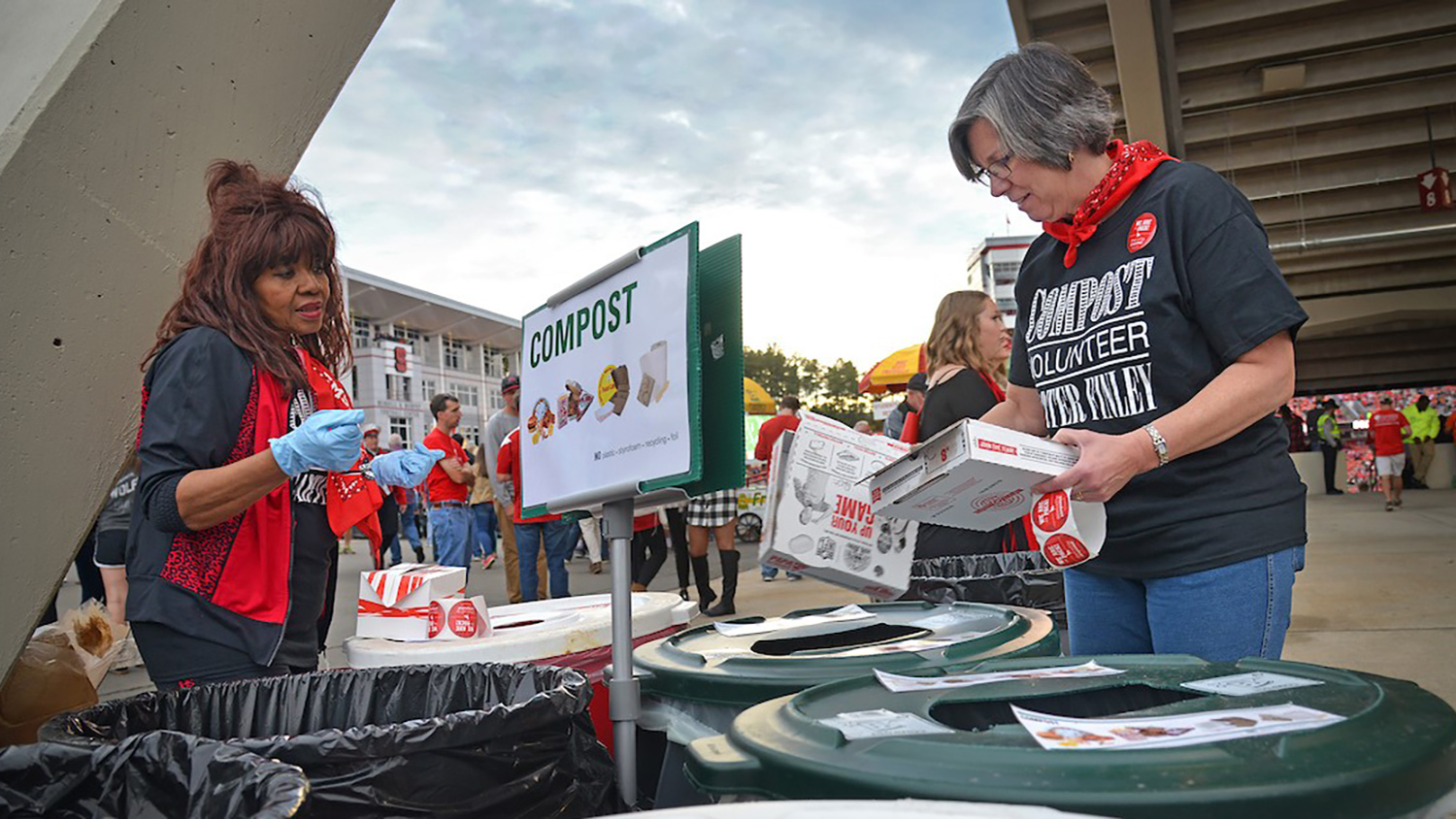 two women help with composting at an NC state event