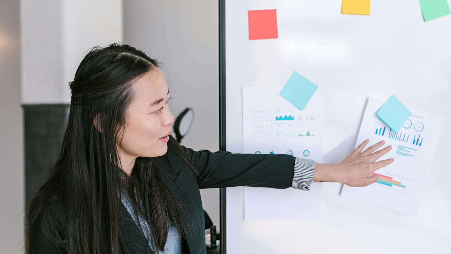 a woman points to graphics on a white board