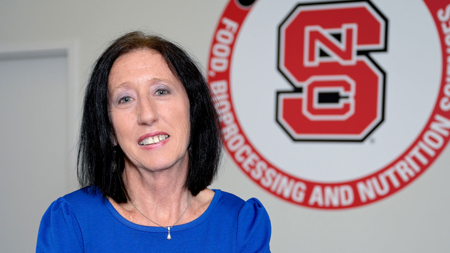 Beth King in front of NC State department mural