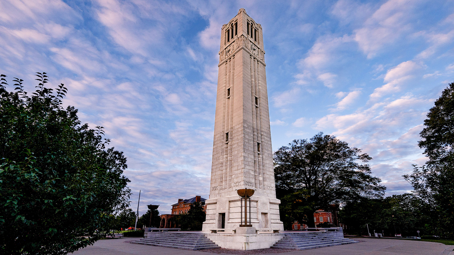 Susan Woodson portrait at the Point on Centennial Campus. The NC State Memorial Belltower rises into a sky of puffy clouds just after sunrise on an October morning. Photo by Becky Kirkland.