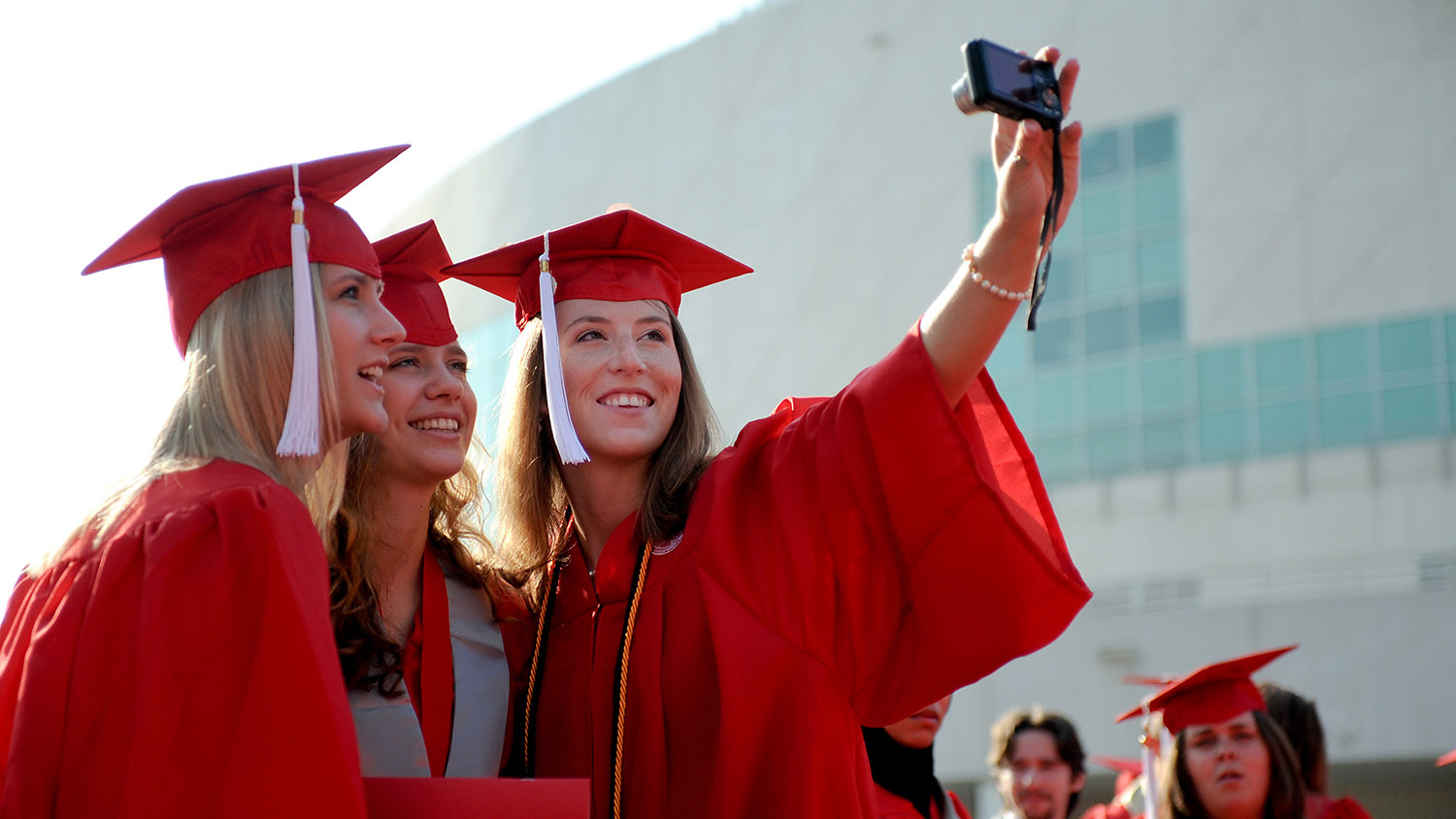 Three female students taking a selfie at NC State graduation ceremony.