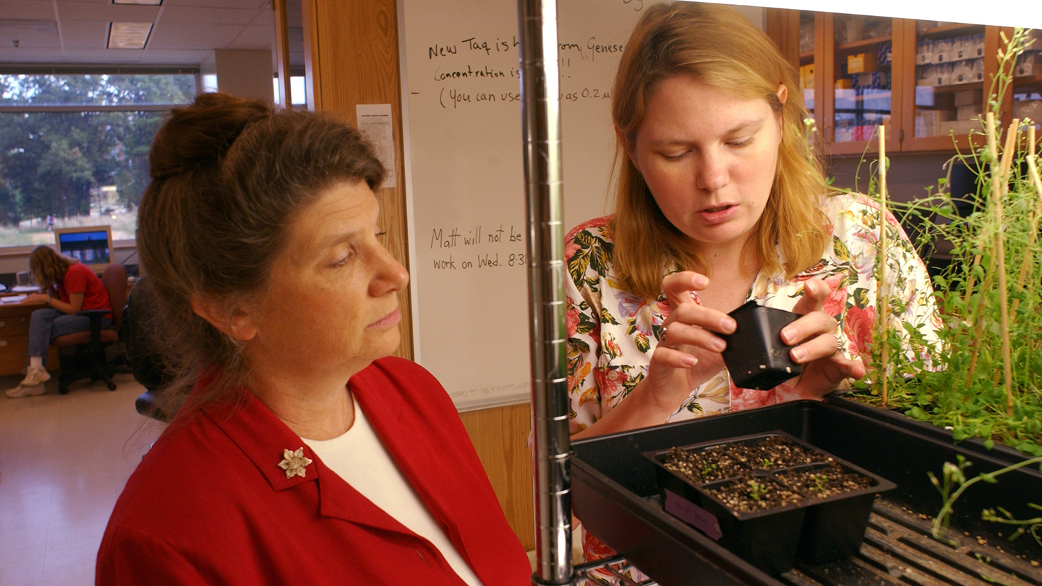 Professor Daub with a student looking at a plant in the classroom.