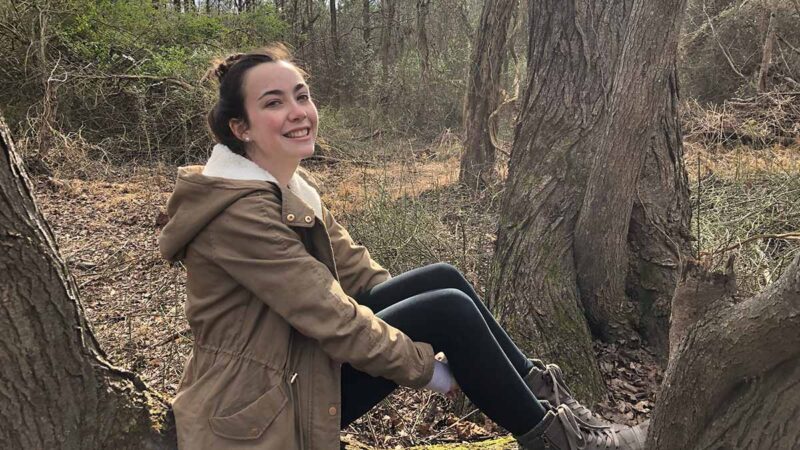 Picture of graduate student Emma Vtipil sitting on a tree
