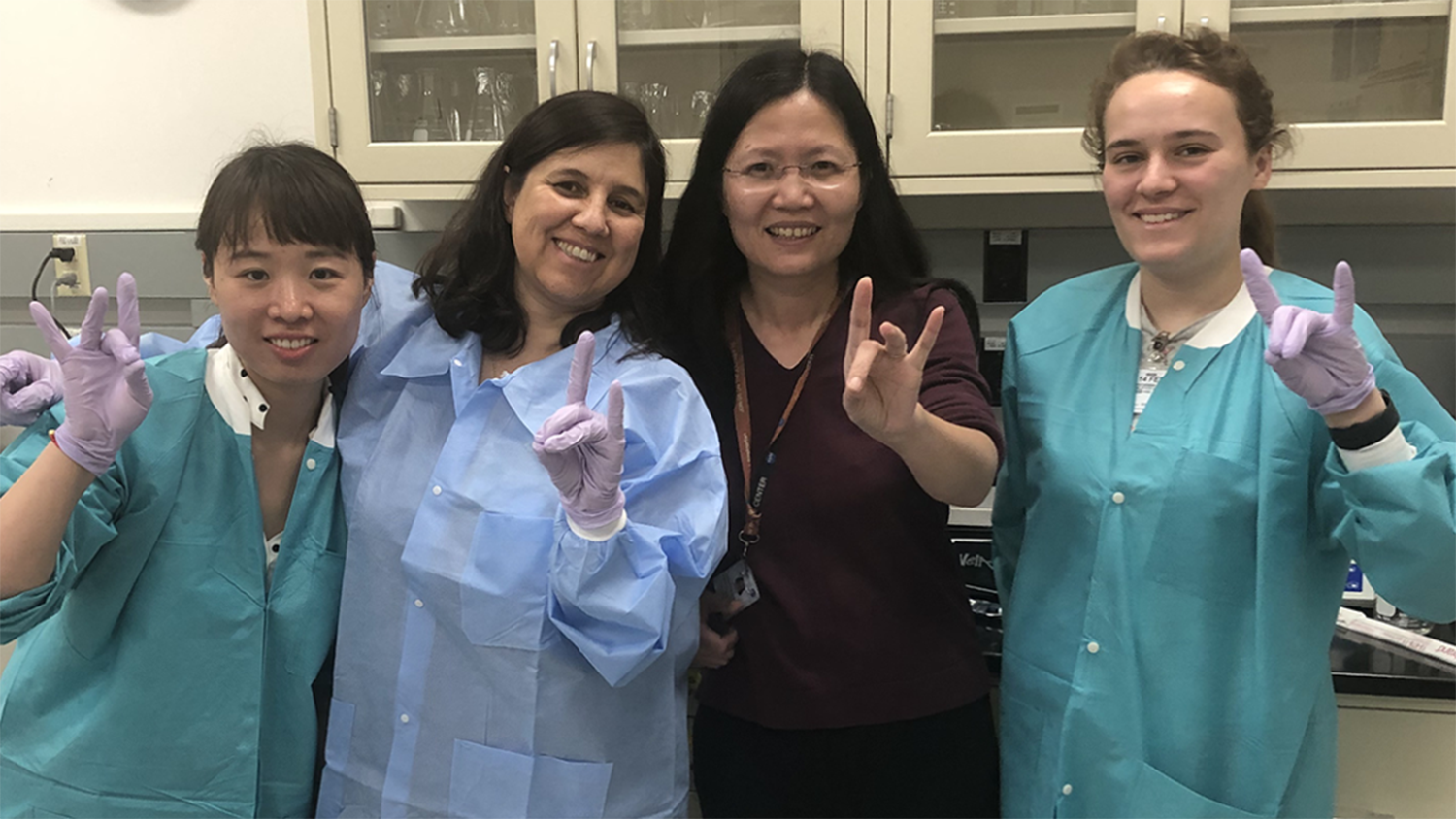 Marcela Rojas-Pierce and her lab pose giving the wolf pack hand sign.