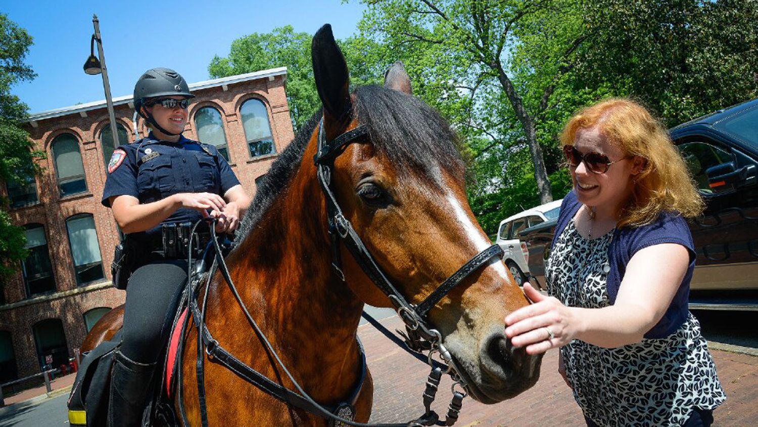 Visitor on campus petting a campus police horse.
