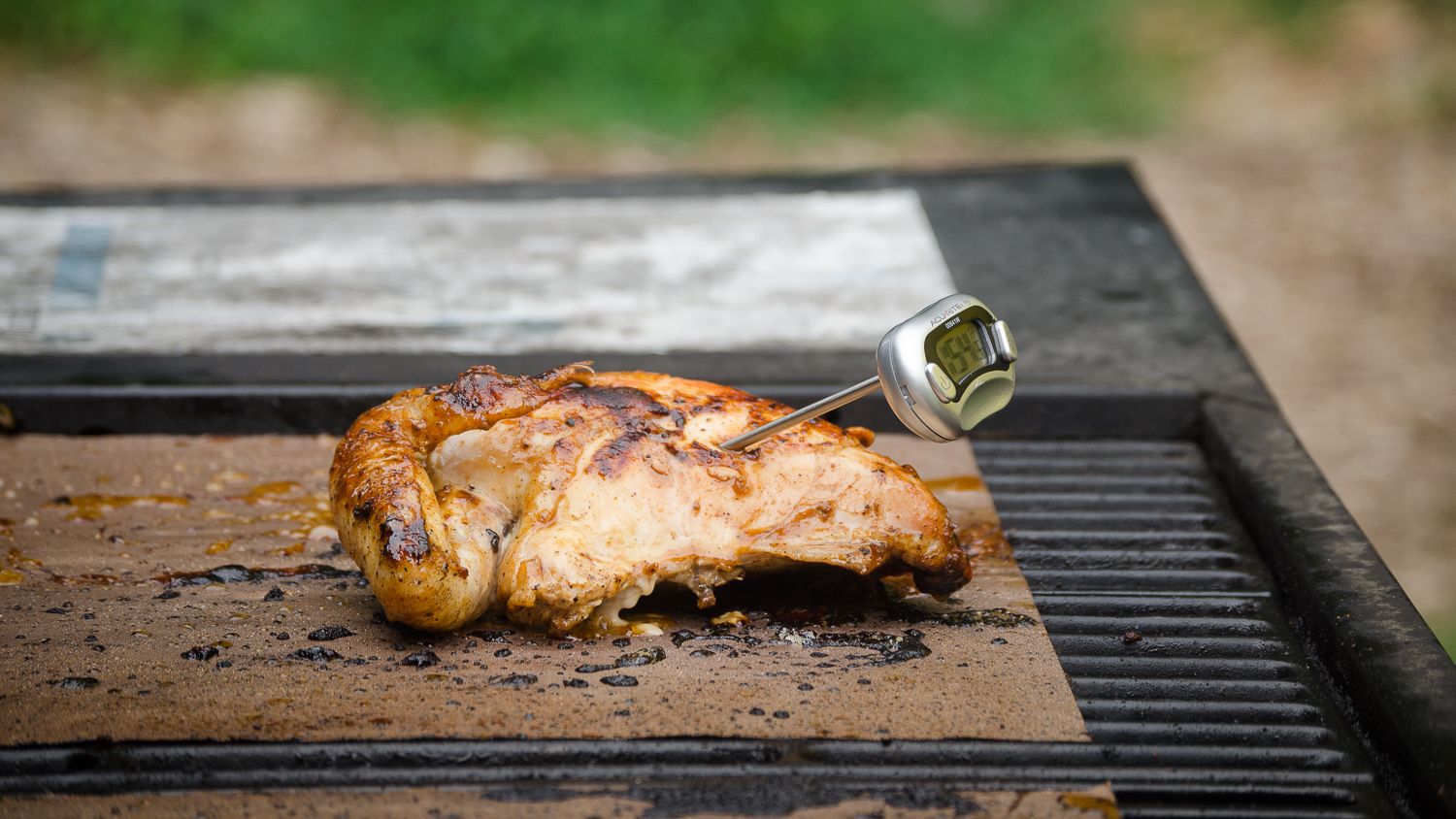 Chicken breast on an open grill with a thermometer in it
