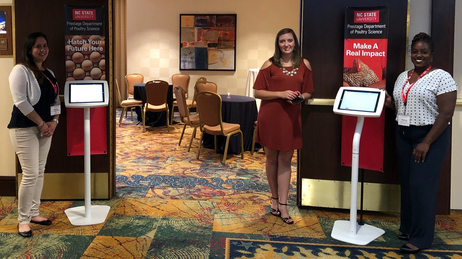 Three women and two kiosks in front of an open reception room