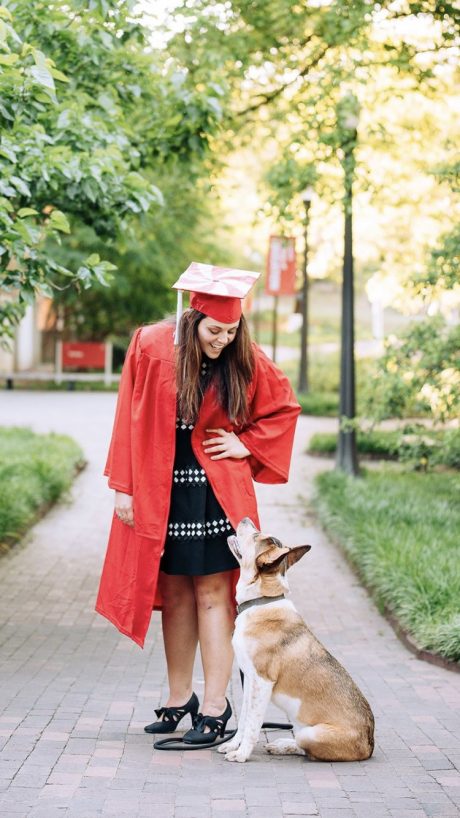 Brittany Wall in red cap and gown with a dog