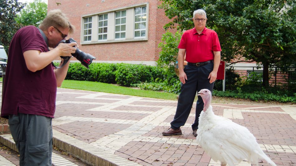 a photographer and a man outside with a white turkey hen