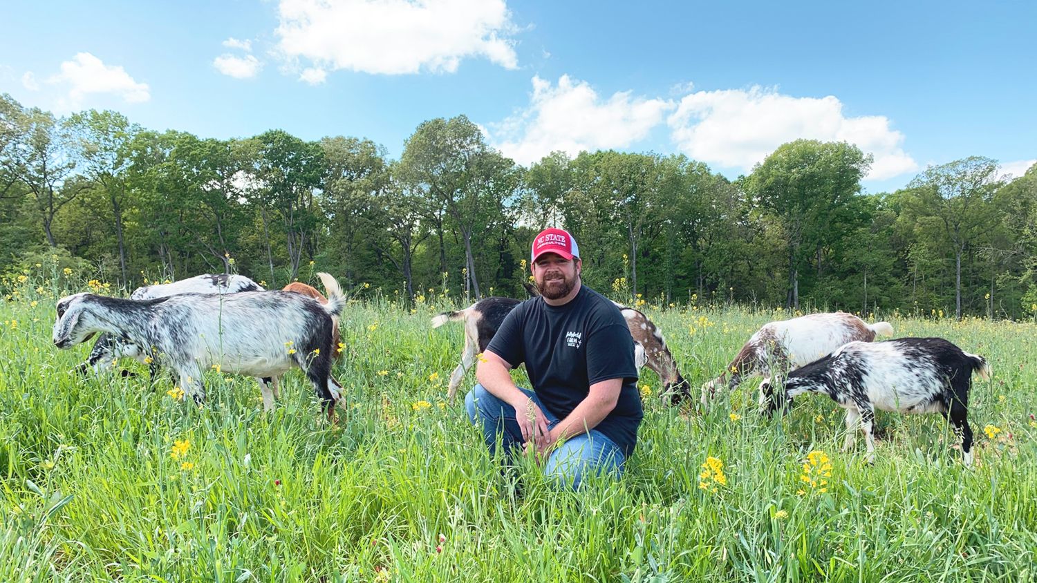 Jonas Asbill in a field with goats