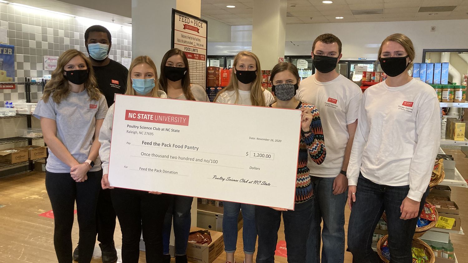 students in masks hold a large check