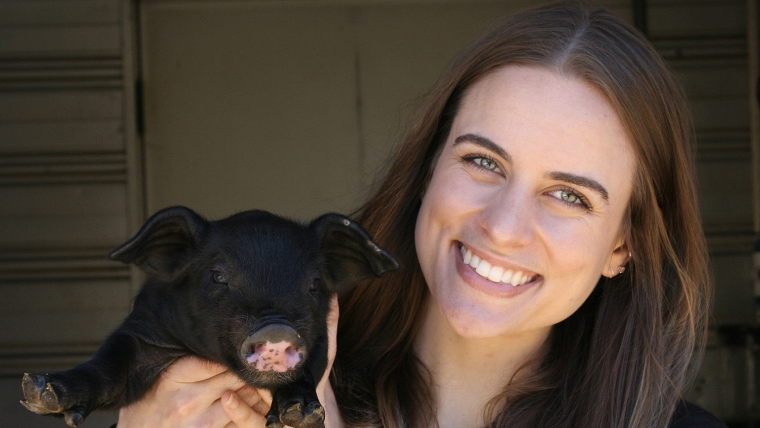 a woman holds a black pig